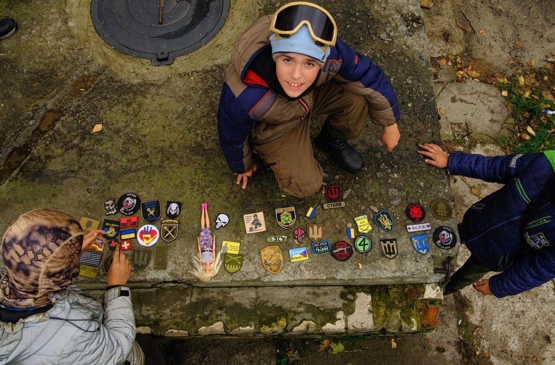 Мальчик Давид (тот, что в защитных очках) меняет военные шевроны на их с ребятами «блокпосте»